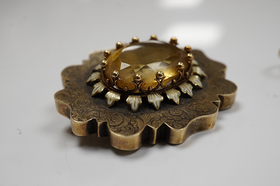 A citrine brooch and a paste and simulant pearl earring, 19th century, comprising: a brooch set with an oval citrine, within a lobed border engraved with floral designs, accented with white enamel, length 3.58cm; and a p